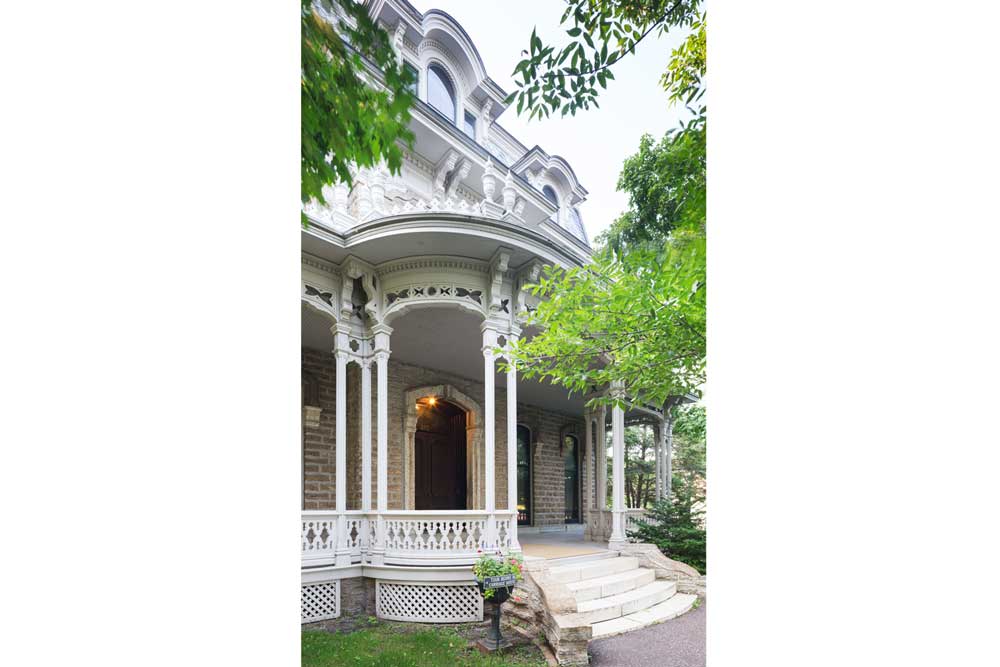 The entryway into the Alexander Ramsey House shows white Victorian architecture with brick incorporated.