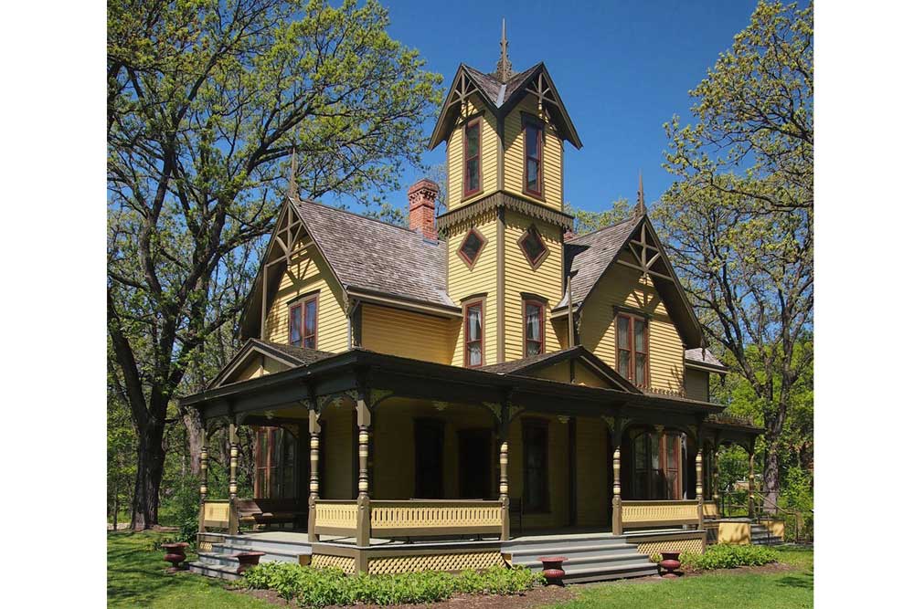 The Burwell House. It's painted yellow, features a wrap-around porch and a tall tower.