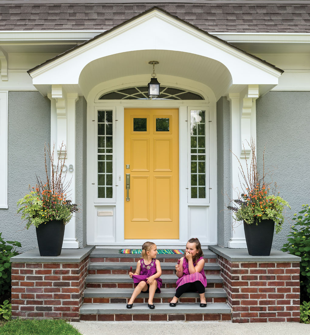 Two young girls having fun sitting on the front steps of their house.