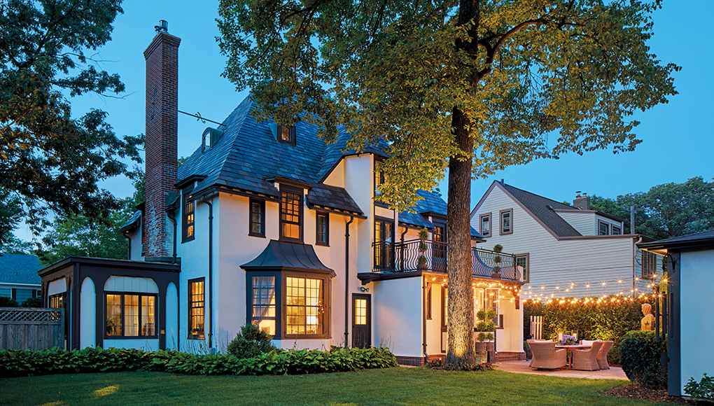 The backside exterior of a home featuring repainted stucco, gray-blue trim and patio with lights strung across.