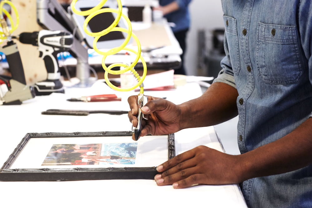 A person putting a frame on a picture at Framebridge.