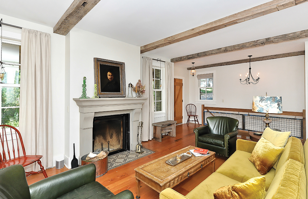 Vintage treasures capture the feel of a mid-19th century home. Both the floor and the mantel are made from recycled materials in a living room designed by Studio Hittle.