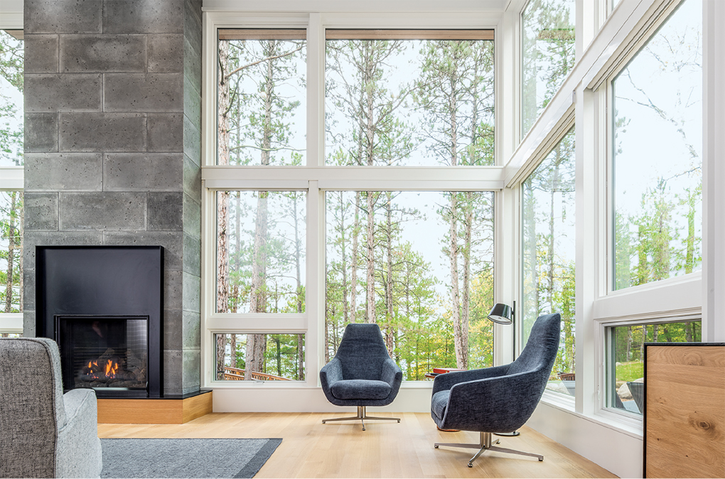 A home designed by Strand Design features a two-story living room with concrete block fireplace.