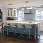 Partners 4, Design A kitchen designed by Nicole Sirek of Partners 4, Design on the 2017 ASID Kitchen Tour. White cabinetry is accented by a blue-tiled backsplash. In the center of the kitchen is a blue-colored island with a white countertop, and is surrounded by blue stools.