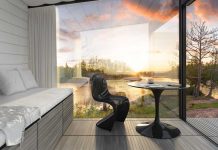 AIA Minnesota Guide to Good Design 2017 A sun room with walls made of glass looks out onto a lake surrounded by a forest as the sun sets.