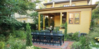 Landscape Architect Frank Fitzgerald’s Minneapolis Garden Retreat A dining table setup on a brick patio in the middle of a backyard garden.