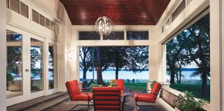 Preserving the Soul of a Lakeside Retreat A semi-outdoor patio features a table and chairs, clerestory windows and large pocket doors with Phantom screens that look out onto a lake.