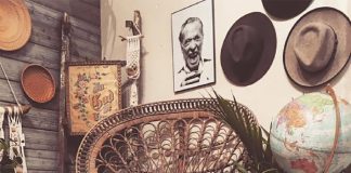 Rustic Charm at Lovegood and Co. Empty brown woven chair surrounded by plant and hats