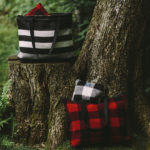 Faribault Woolen Mill Introduces Great-for-Gifts Goods Patterned totes by Faribault Woolen Mill sitting on a tree stump.