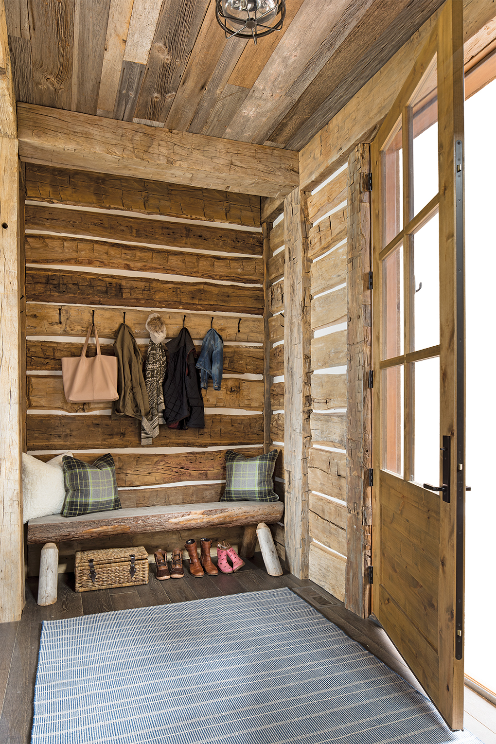 The entry's reclaimed wood, log walls with chinking, and rough-hewn beams set the tone for this homey lake place.