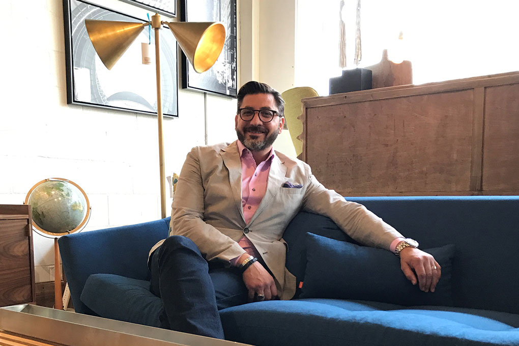 A portrait of Gregory Rich sitting on a blue sofa.
