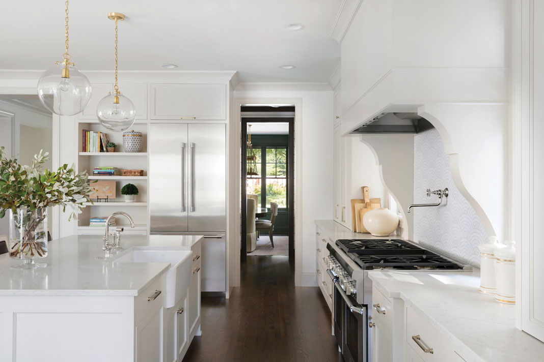 In the kitchen, modern light fixtures hang over the marble-like island, which includes a large farmhouse sink. Part of Midwest Home's 2018 Luxury Home Tour.