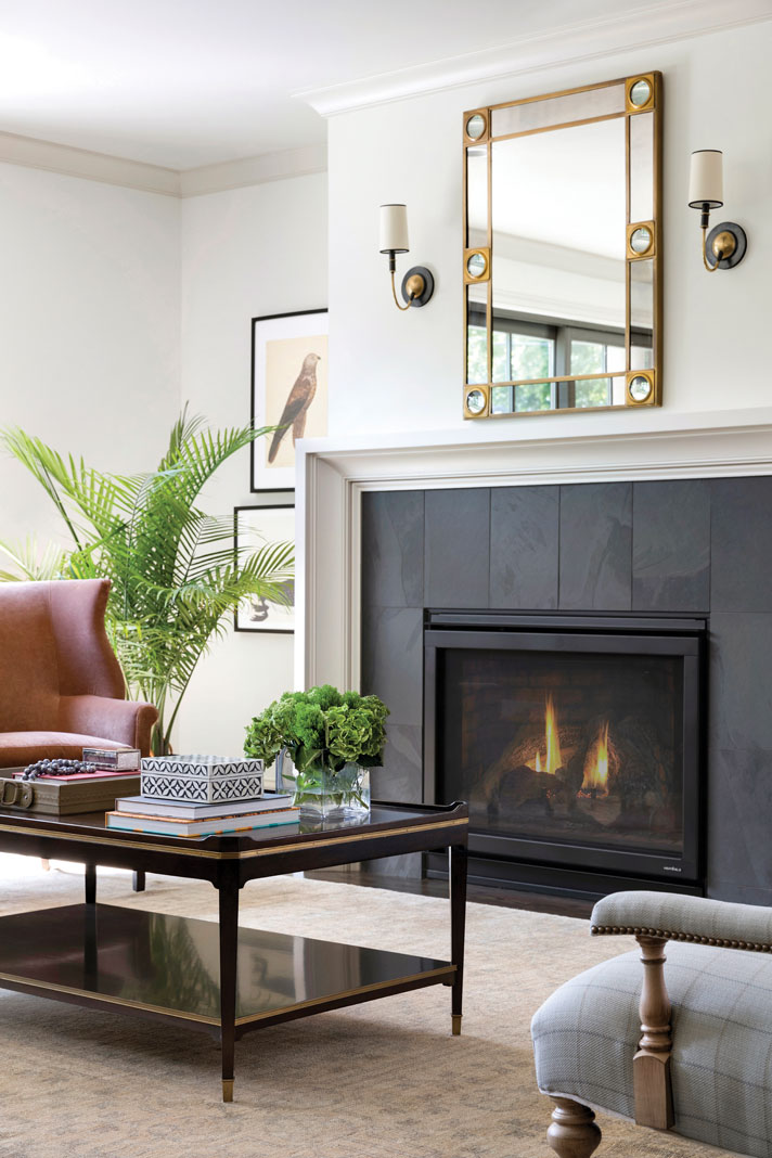 A sleek black stone fireplace acts as the focal point of the home’s great room, while an overhead mirror, flanked by twin sconces, accentuates its simple elegance. Part of Midwest Home's Luxury Home Tour 2018.