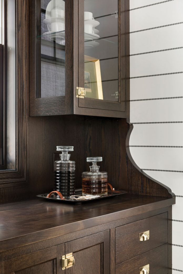 A pantry in a home on Midwest Home's 2018 Luxury Home Tour that shows alcohol sitting on a dark wood cabinet.