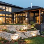 The kitchen, great room, and master suite of a home all look out onto an outdoor living space that serves as an extension of the house. Stone steps lead down a terrace to the backyard, which contains a patio, fireplace, and grilling area ideal for entertaining. Part of Midwest Home's 2018 Luxury Home Tour.