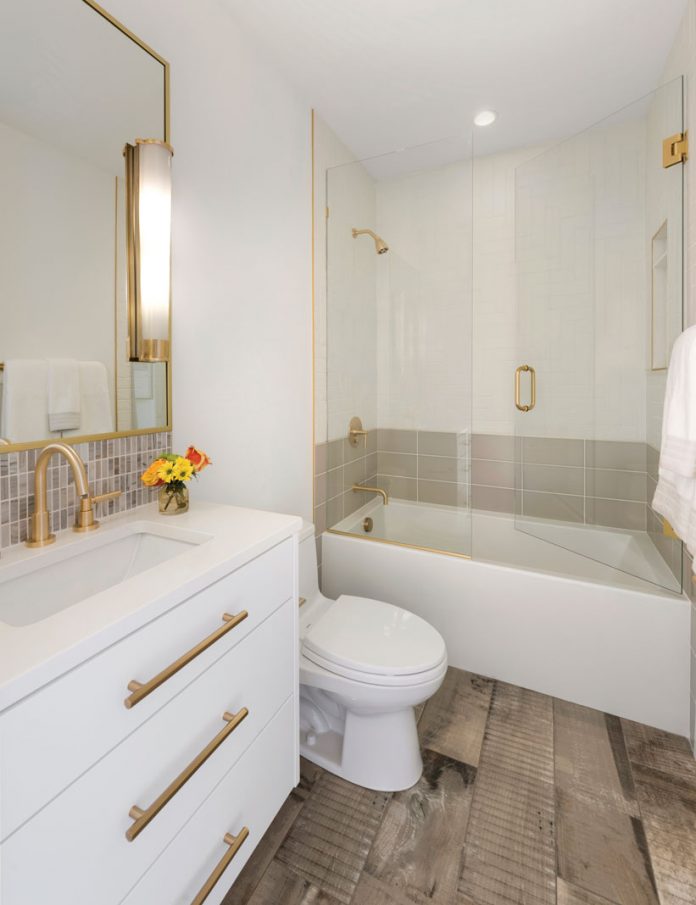 An all white bathroom in a home on Midwest Home's 2018 Luxury Home Tour that shows vanity, toilet, and tub with shower.