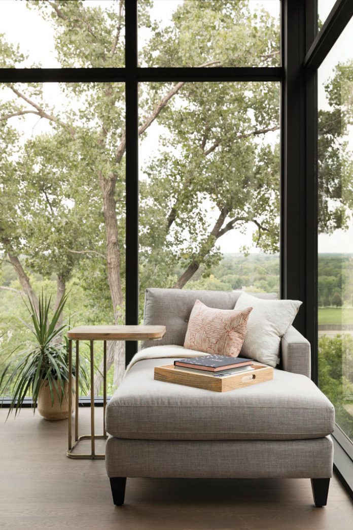 Lounge seating next to a floor-to-ceiling window over looking trees in a home on Midwest Home's 2018 Luxury Home Tour.