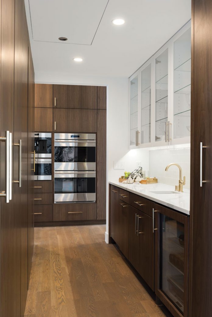 The pantry in a home on Midwest Home's 2018 Luxury Home Tour that features wood flooring and cabinetry with a white sink.
