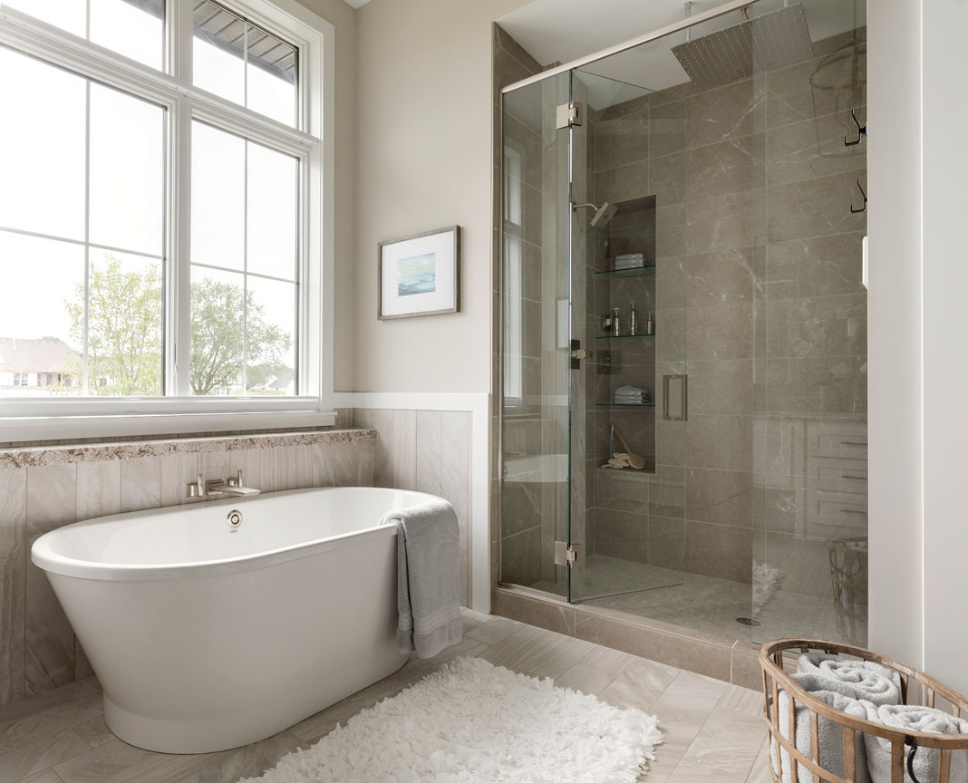 A sliding barn door that leads to a bathroom complete with soaking tub and soothing rain shower. Part of Midwest Home's 2018 Luxury Home Tour.