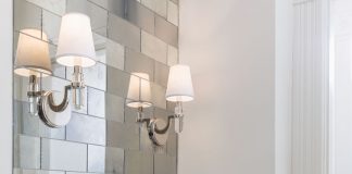 Magic Mirror on the Wall A bathroom with mirrored tiles, white sink and wall sconce light.