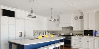 A wood floor kitchen with white cabinetry and a pop of blue paint on the island.
