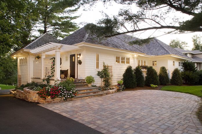 Early morning light brightens a white house and brick driveway