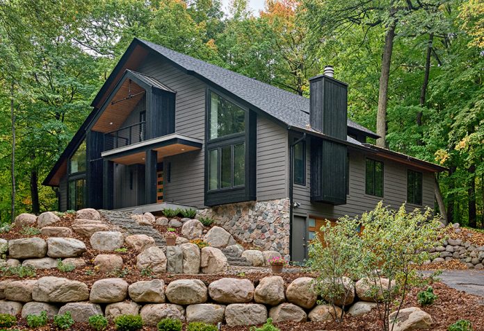 large rock retaining wall with dark grey home