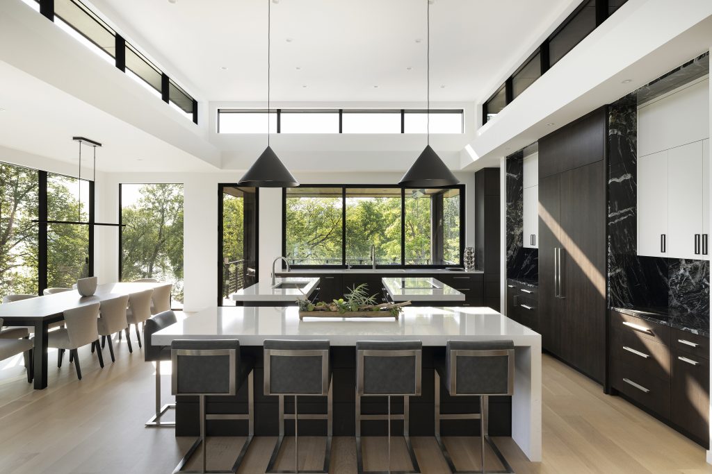 Soaring 14-foot ceilings create a sense of openness, while three kitchen islands and a dramatic floor-to-ceiling fireplace establish striking focal points in this kitchen.