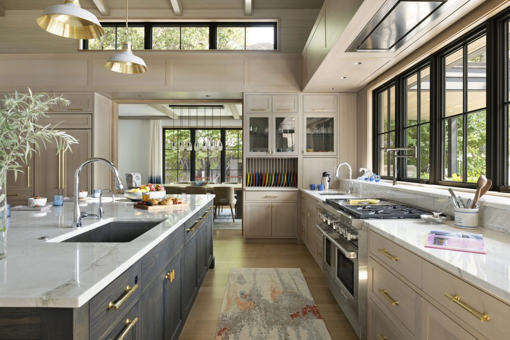 This kitchen features custom rift-cut white oak millwork and cabinetry accented by a dark-stained center island, durable quartzite countertops, and white oak flooring