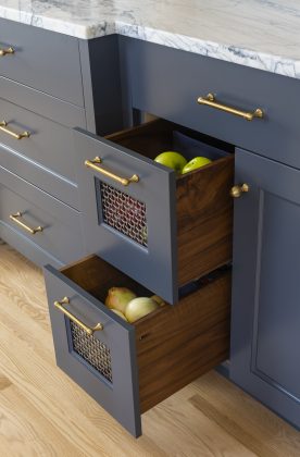 Soft brass hardware details in the kitchen pair with the contrasting cabinet hues for a sophisticated and eclectic look.
