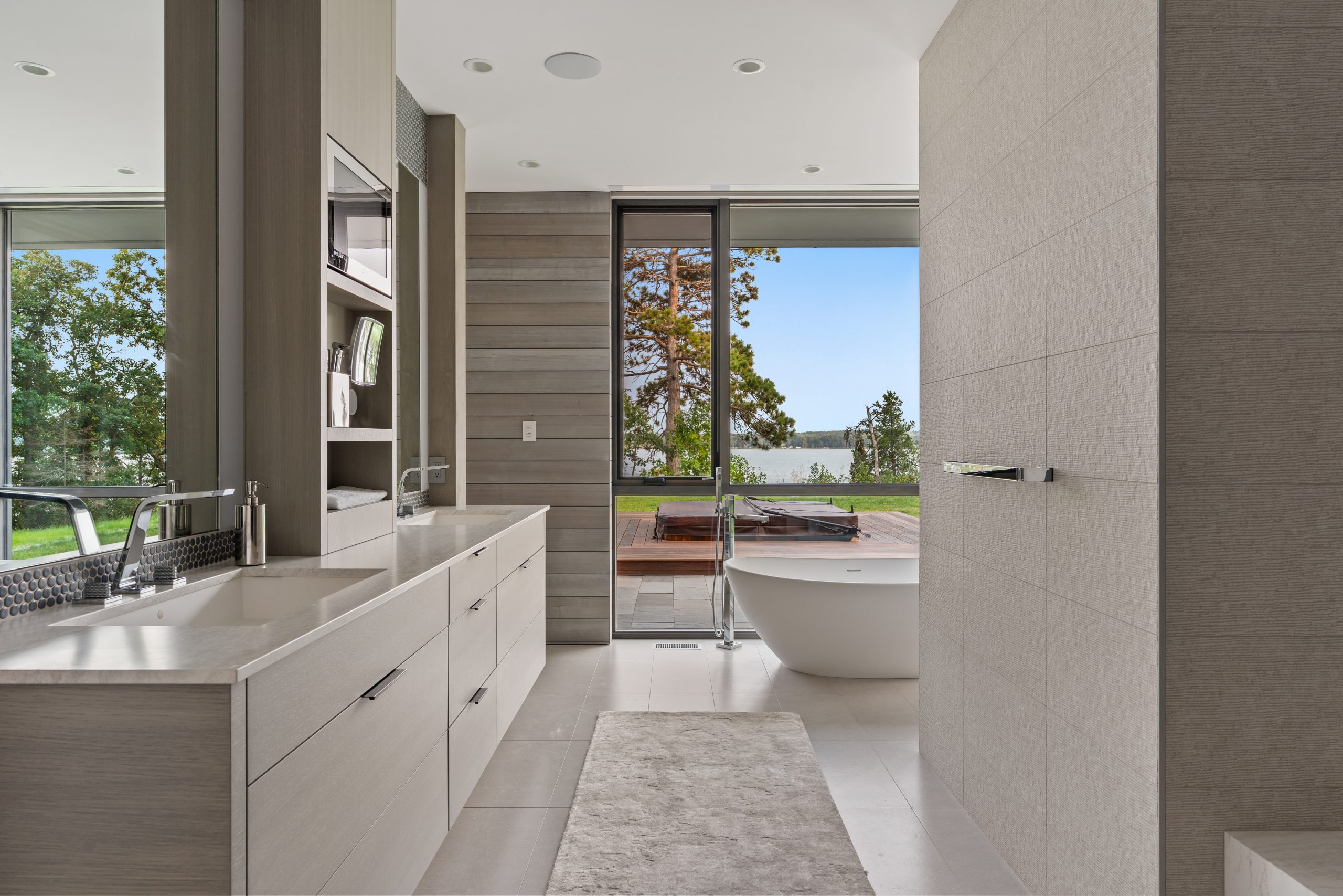 The primary bath looks out to the lake and features thoughtful storage and elegant tile and hardware selections.