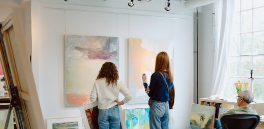 Sales + Events: May Is For Foodies, Green Thumbs, and Creatives Visitors select paintings for sale at an Art-A-Whirl artist studio