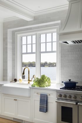 The new kitchen features serene views of the lake, enameled cabinetry, and a pearlescent tile backsplash.