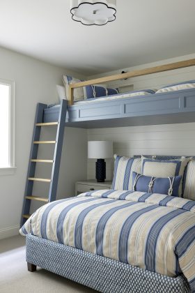 Downstairs, the playful bunk room, featuring shiplap details and integrated storage, offers a fun spot for the grandkids.