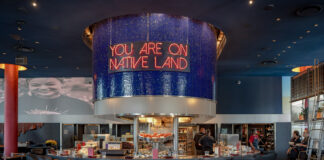 Design-Forward Twin Cities Restaurants Bring Dining to New Heights IndÃgena by Owamni interior with "You Are On Native Land" sign above the central bar. August 19, 2026