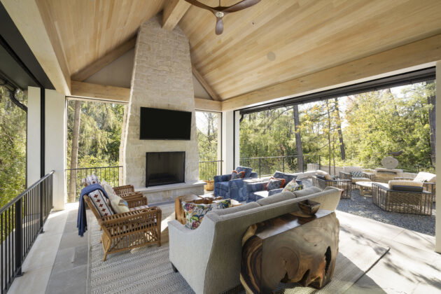 An indoor-outdoor patio encourages year-round hosting and lounging amid the sights and sounds of nature. Earthy materials blend the space with the outdoors, while brightly colored fabrics give the area visual interest and artful personality.