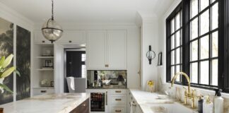 Craftsmanship Shines in This Remodel Within a Century-Old Summit Avenue Home The kitchen features light cabinetry, rich brass tones, Borghini Marble countertops, a unique wall mural, a large island, and creative storage solutions.