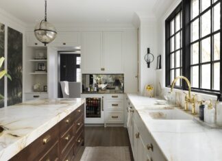 The kitchen features light cabinetry, rich brass tones, Borghini Marble countertops, a unique wall mural, a large island, and creative storage solutions.