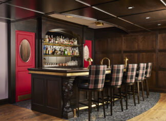 Plaid upholstery complements brass hardware and rich wood, evoking images of faraway European pubs.
